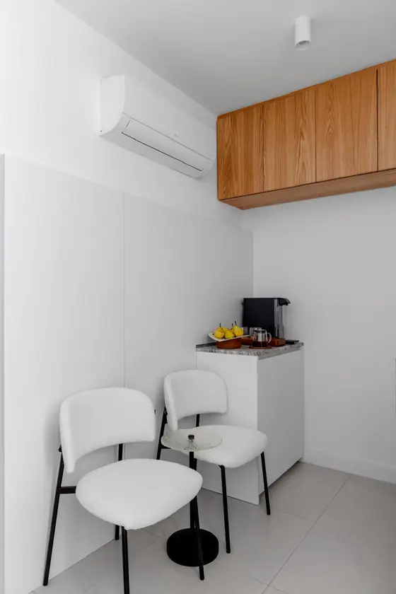 Sala de espera do consultório com duas poltronas claras, mesa de apoio e estação de café.